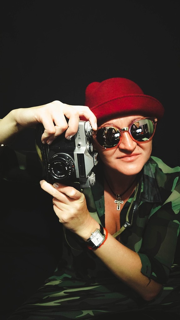 Portrait d'un photographe créatif portant un béret rouge et des lunettes de soleil, tenant un appareil photo vintage, prêt à capturer des moments artistiques